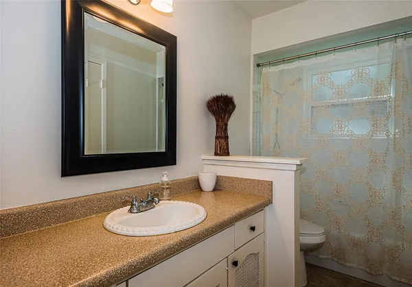 a bathroom with a granite countertop sink toilet a mirror and shower
