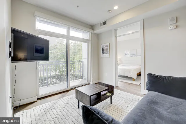 a living room with furniture a flat screen tv and a floor to ceiling window