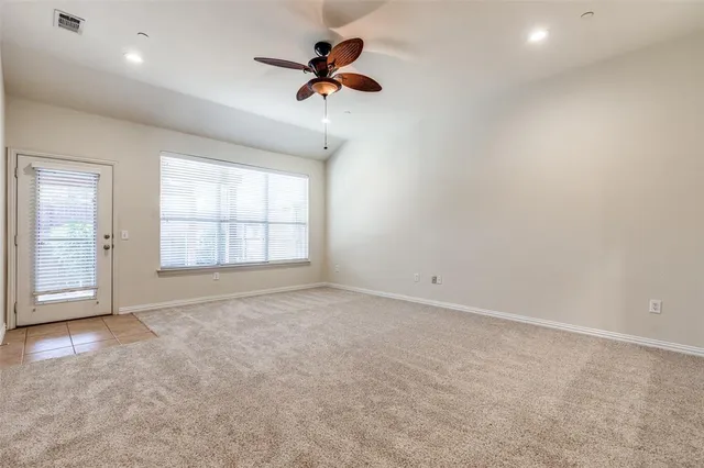 an empty room with windows and ceiling fan