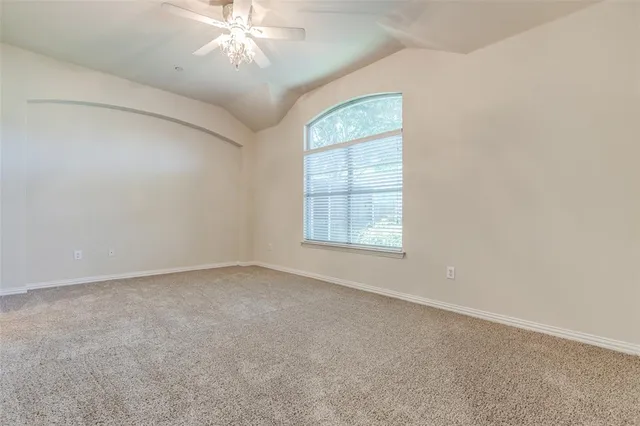 an empty room with windows and chandelier fan