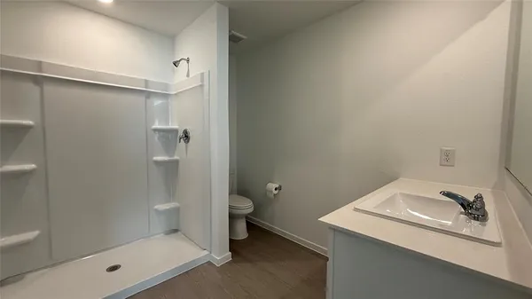a bathroom with a granite countertop sink a toilet and shower