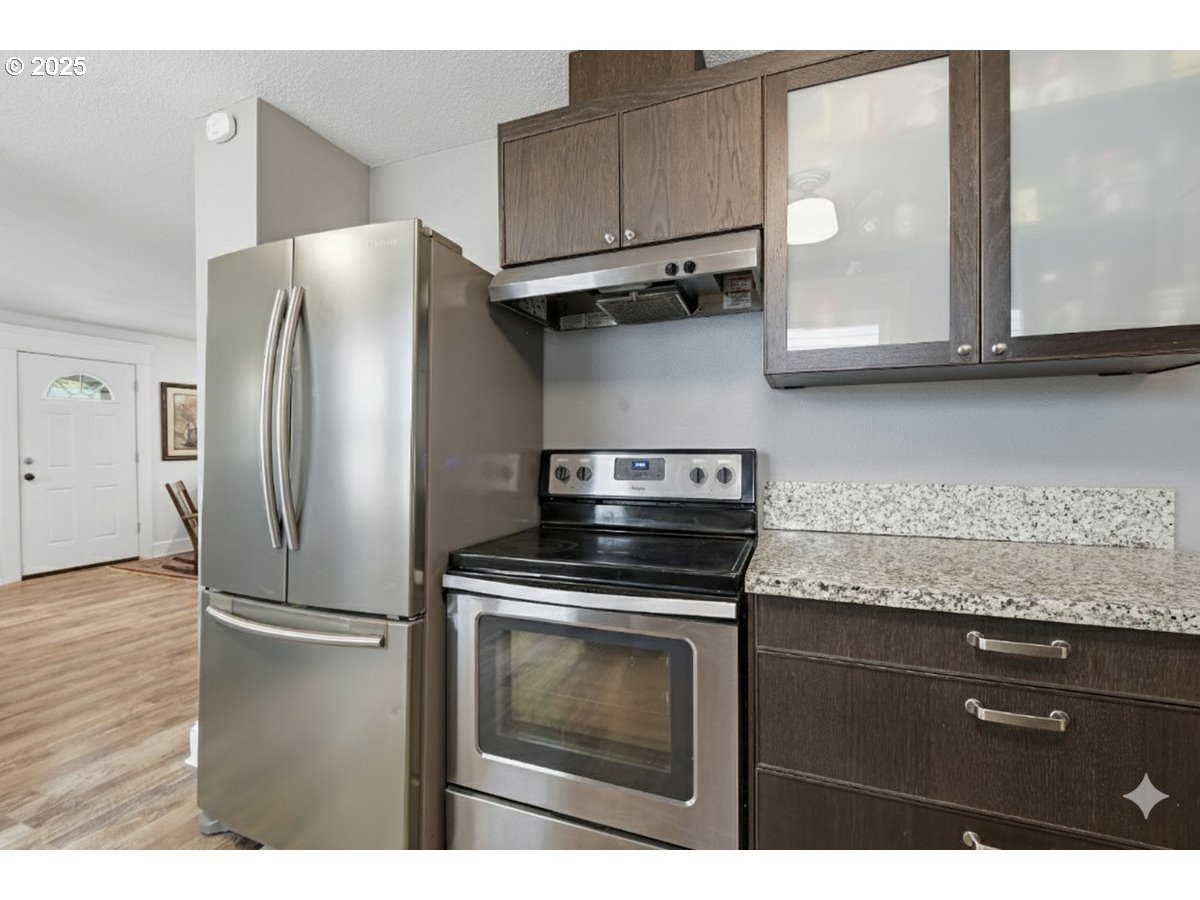 8813 Northeast Ward Street Portland, OR 97220 - Photo 32 of 32 a kitchen with granite countertop a refrigerator stove and microwave