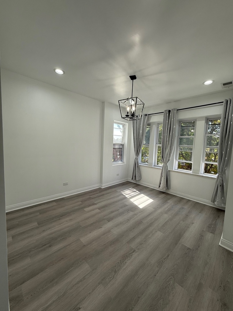 4357 South Whipple Street, Unit 2 Chicago, IL 60632 - Photo 5 of 17 an empty room with wooden floor and chandelier