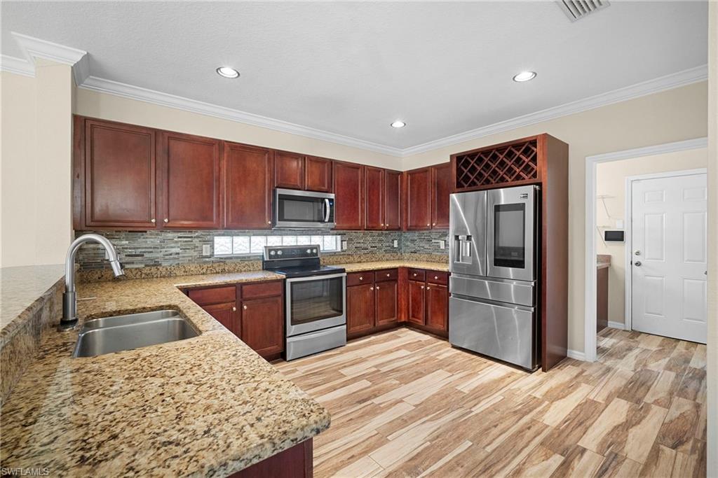 8542 Sumner Avenue, Unit 1 Fort Myers, FL 33908 - Photo 7 of 18 a kitchen with stainless steel appliances granite countertop a refrigerator sink and cabinets