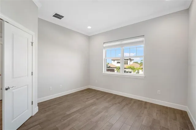 a view of an empty room with window and wooden floor