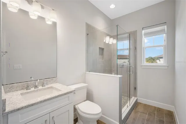 a bathroom with a granite countertop sink mirror vanity and toilet