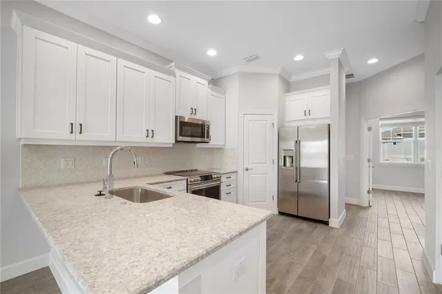 a kitchen with stainless steel appliances granite countertop a refrigerator a sink a stove and oven with wooden floor