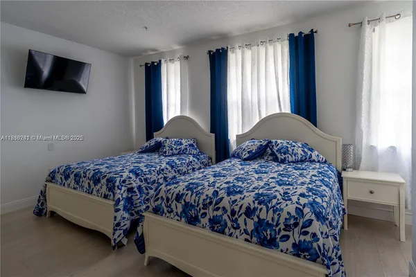 a bedroom with two beds window and a flat screen tv