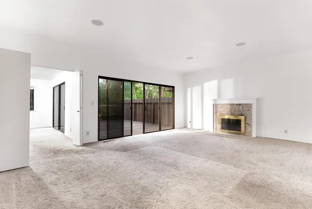 a view of an empty room with a fireplace and a window