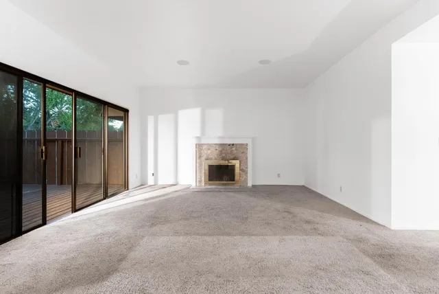 a view of an empty room with a fireplace and a window