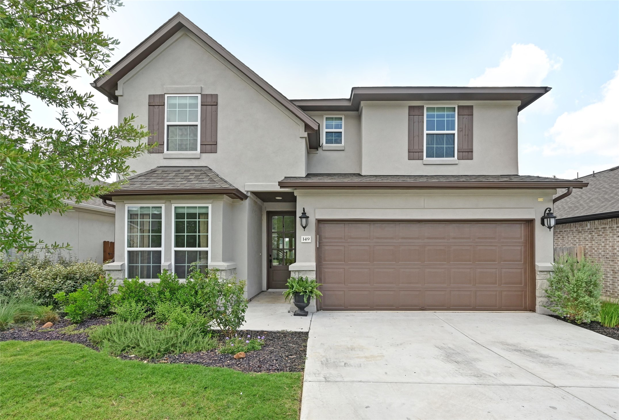 Contemporary stucco exterior featuring a bay window, decorative shutters, a two-car garage, and a covered entry