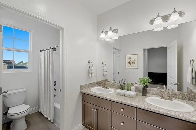 a bathroom with a granite countertop sink a toilet and a mirror
