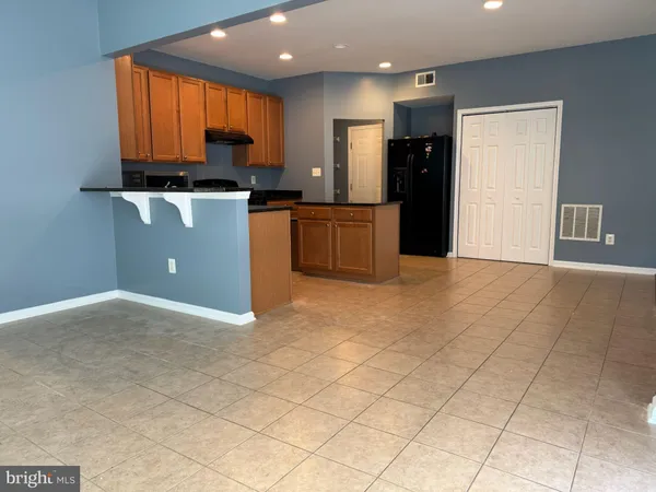 a kitchen with kitchen island granite countertop a stove top oven a sink a counter space and cabinets