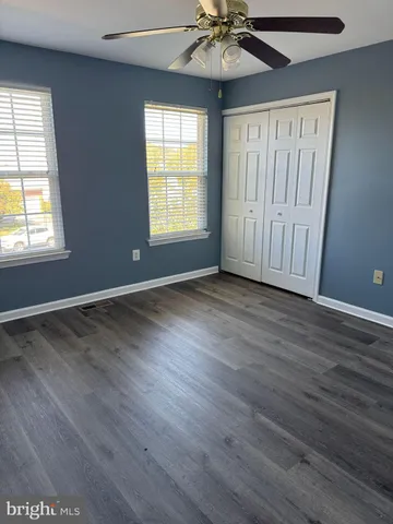 an empty room with wooden floor fan and windows