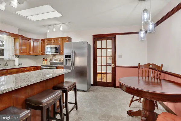 a kitchen with kitchen island a dining table chairs stainless steel appliances and cabinets