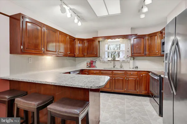 a kitchen with stainless steel appliances granite countertop a sink refrigerator and cabinets