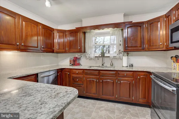 a kitchen with stainless steel appliances granite countertop wooden cabinets a sink and dishwasher a stove with wooden cabinets