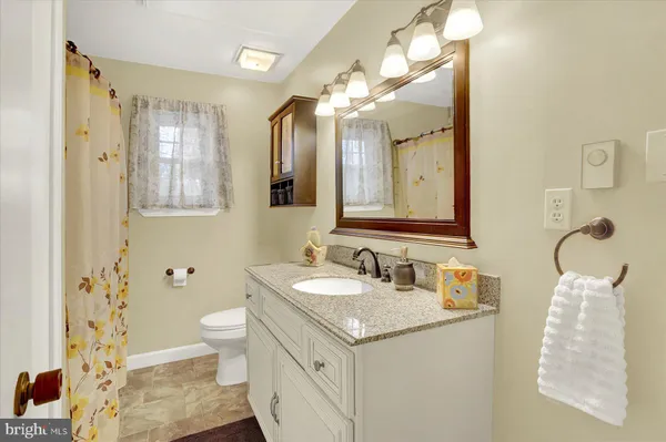 a bathroom with a granite countertop sink mirror and a toilet