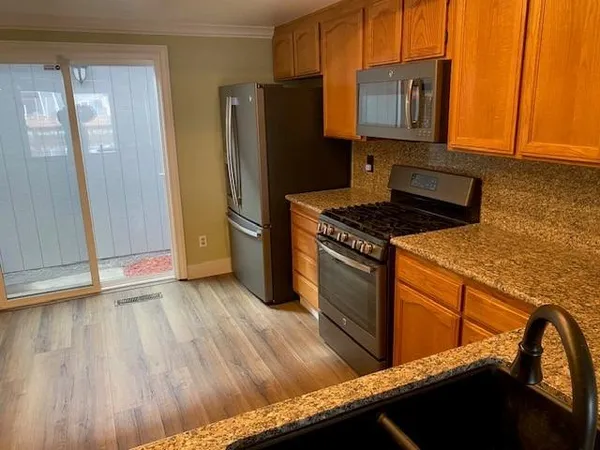 a kitchen with granite countertop wooden cabinets and a stove top oven