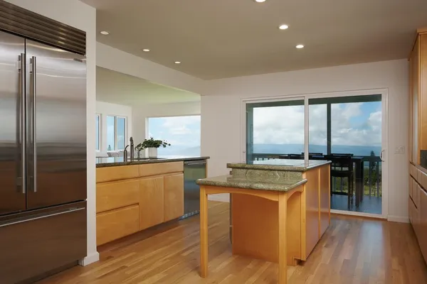 a kitchen with stainless steel appliances granite countertop a refrigerator a stove and a sink with wooden floor