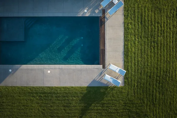 an aerial view of a house with a yard lake and trees all around