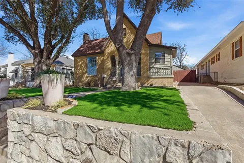 a front view of a house with garden and trees