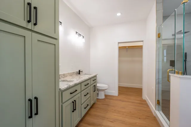 a bathroom with a granite countertop sink a toilet and shower