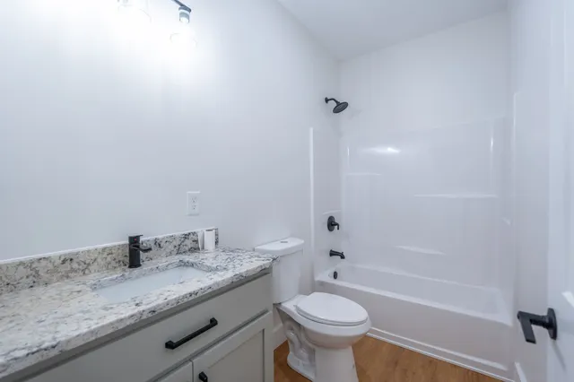 a bathroom with a granite countertop sink a toilet and bathtub