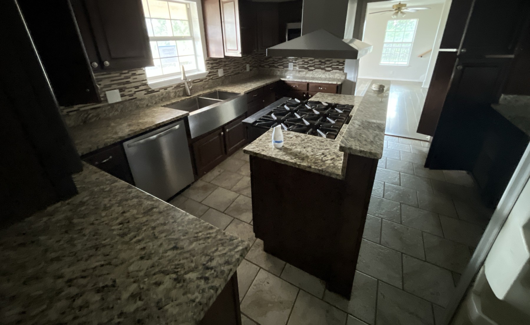 A well-appointed kitchen features a large center island cooktop and rich granite countertops throughout.