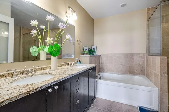 a bathroom with a granite countertop bathtub a double vanity sink and a mirror