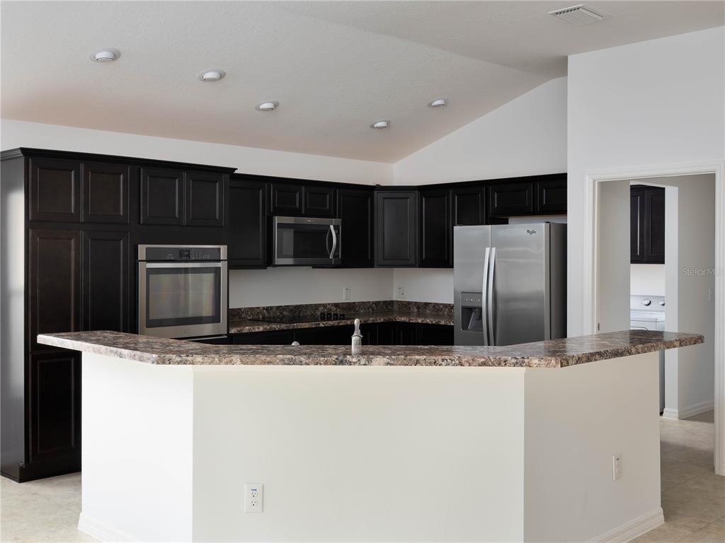3942 Zenith Loop The Villages, FL 32163 - Photo 11 of 31 a kitchen with stainless steel appliances granite countertop a sink a stove a microwave and a refrigerator