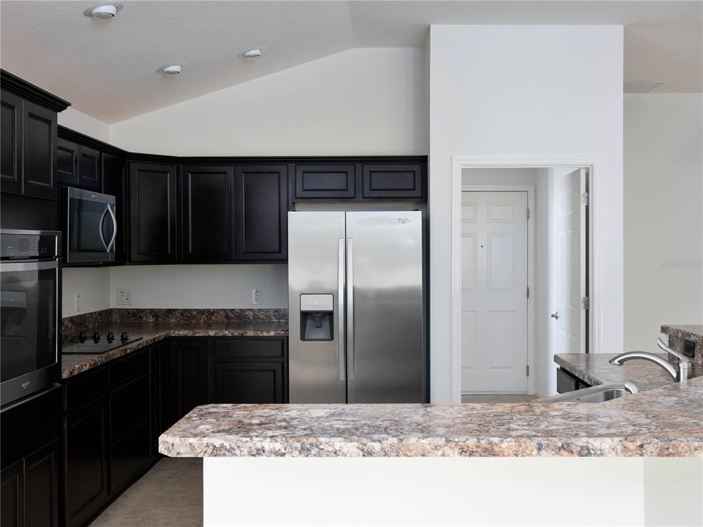 3942 Zenith Loop The Villages, FL 32163 - Photo 12 of 31 a kitchen with kitchen island granite countertop a refrigerator and a stove top oven
