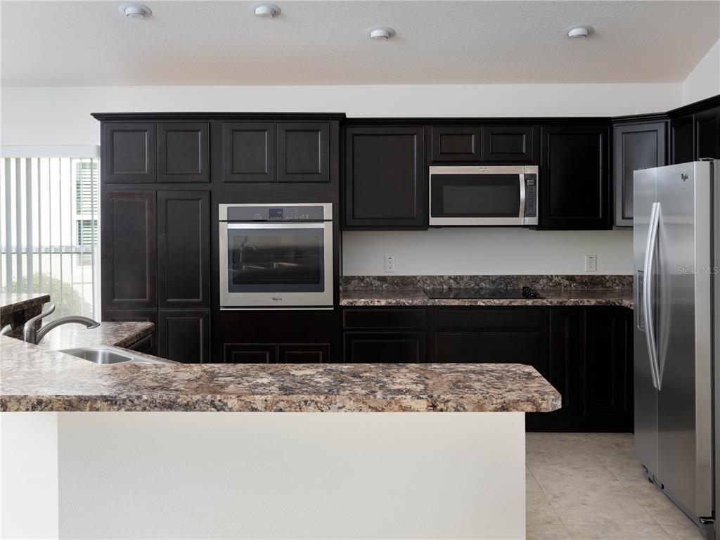 3942 Zenith Loop The Villages, FL 32163 - Photo 13 of 31 a kitchen with granite countertop a refrigerator and a stove top oven