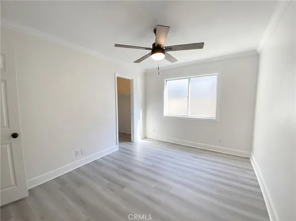 an empty room with wooden floor ceiling fan and windows