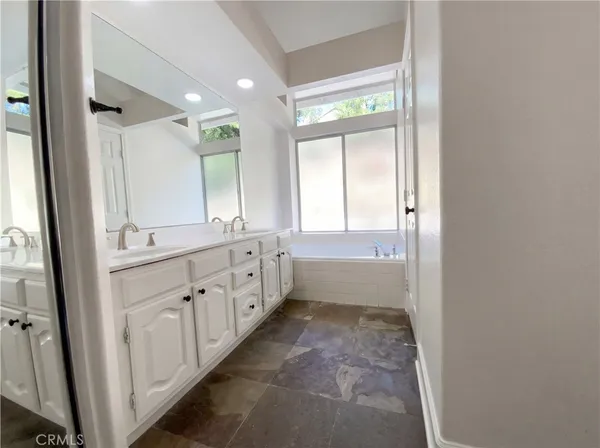 a bathroom with a double vanity sink and mirror with window