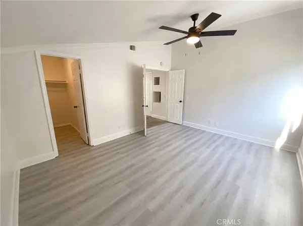 an empty room with wooden floor and a ceiling fan