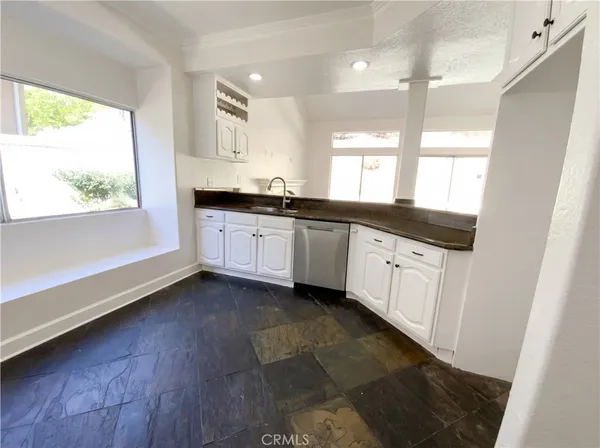 a large kitchen with granite countertop a large window a sink and cabinets