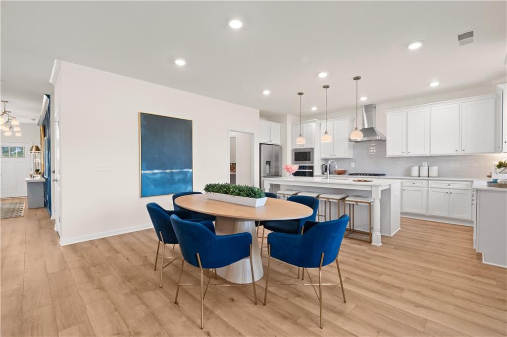 200 Chiswick Loop Stockbridge, GA 30281 - Photo 15 of 44 a kitchen with a dining table chairs and wooden floor