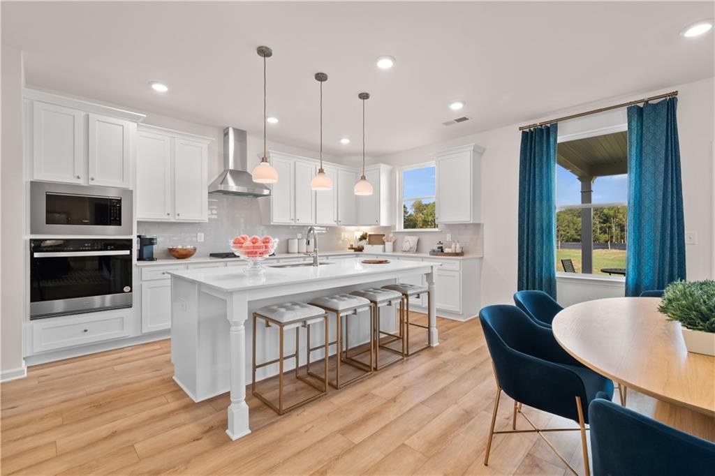 200 Chiswick Loop Stockbridge, GA 30281 - Photo 16 of 44 a kitchen with stainless steel appliances kitchen island granite countertop a kitchen island hardwood floor sink stove dining table and chairs