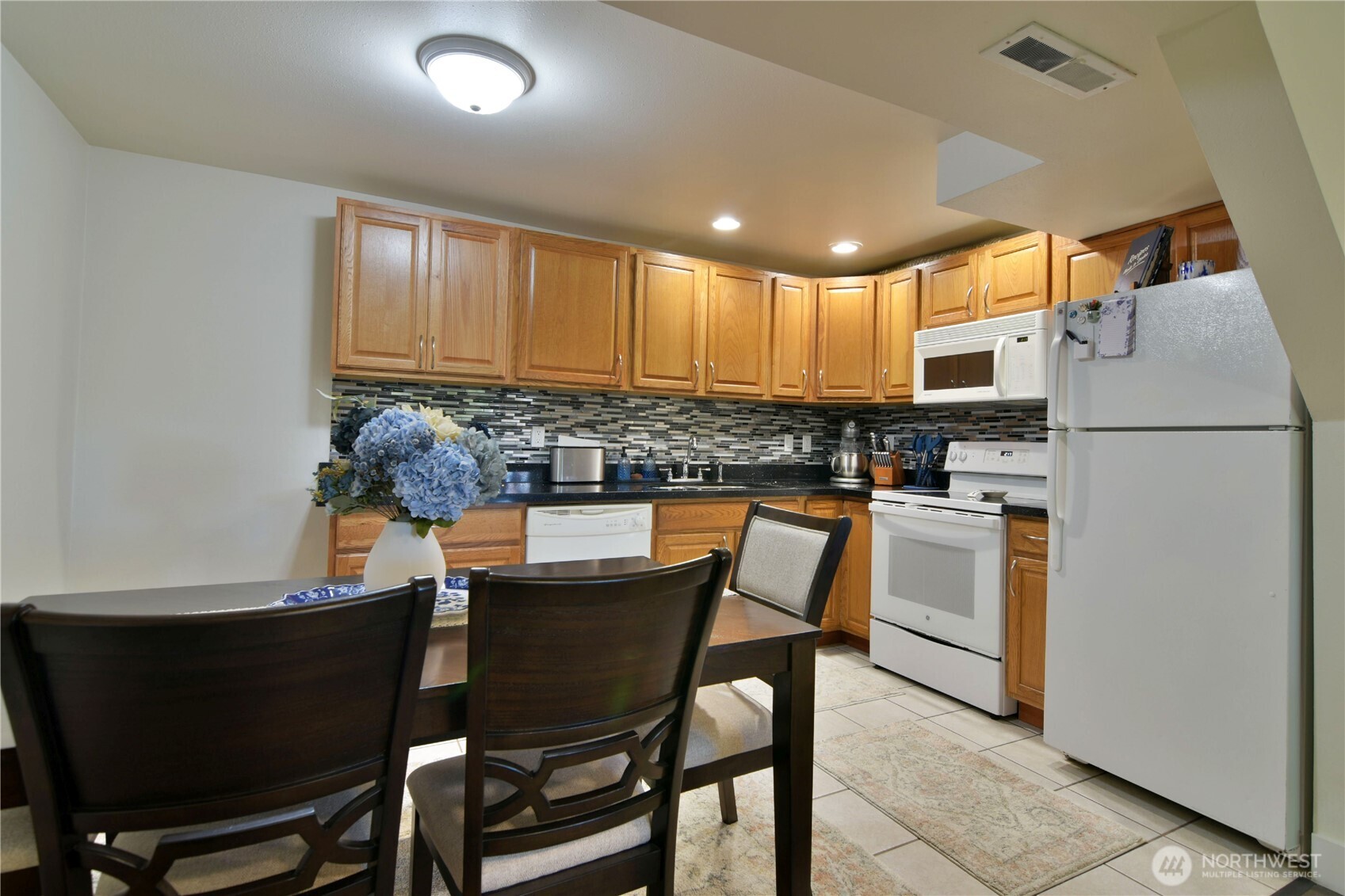 23116 80th Place West Edmonds, WA 98026 - Photo 26 of 34 a kitchen with stainless steel appliances granite countertop a table chairs and a refrigerator