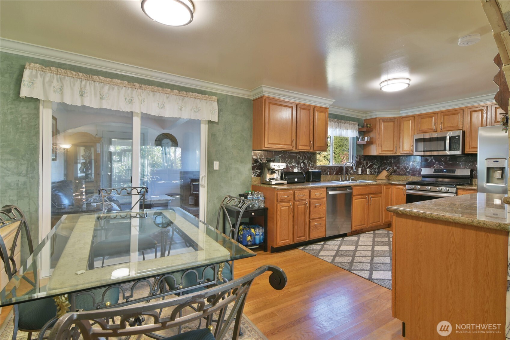 23116 80th Place West Edmonds, WA 98026 - Photo 7 of 34 a kitchen with stainless steel appliances granite countertop a stove top oven a sink dishwasher a dining table and chairs with wooden floor
