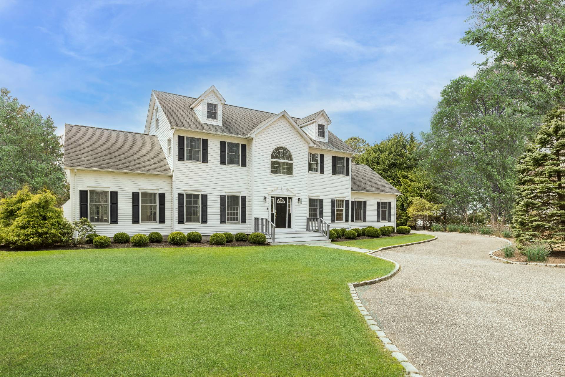 a front view of a house with a garden and trees