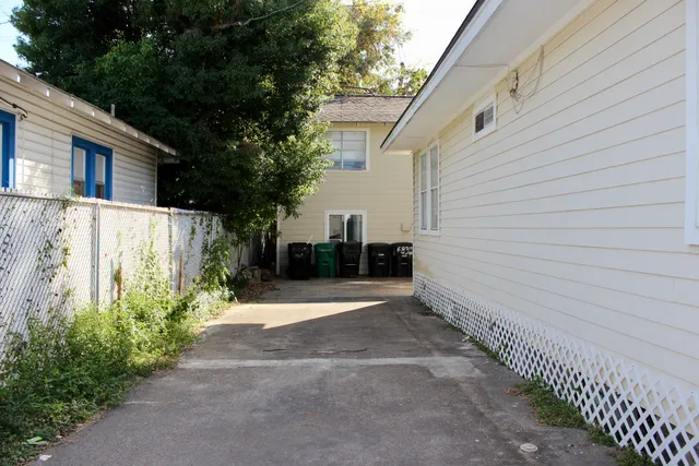 a view of a pathway with house and wooden fence