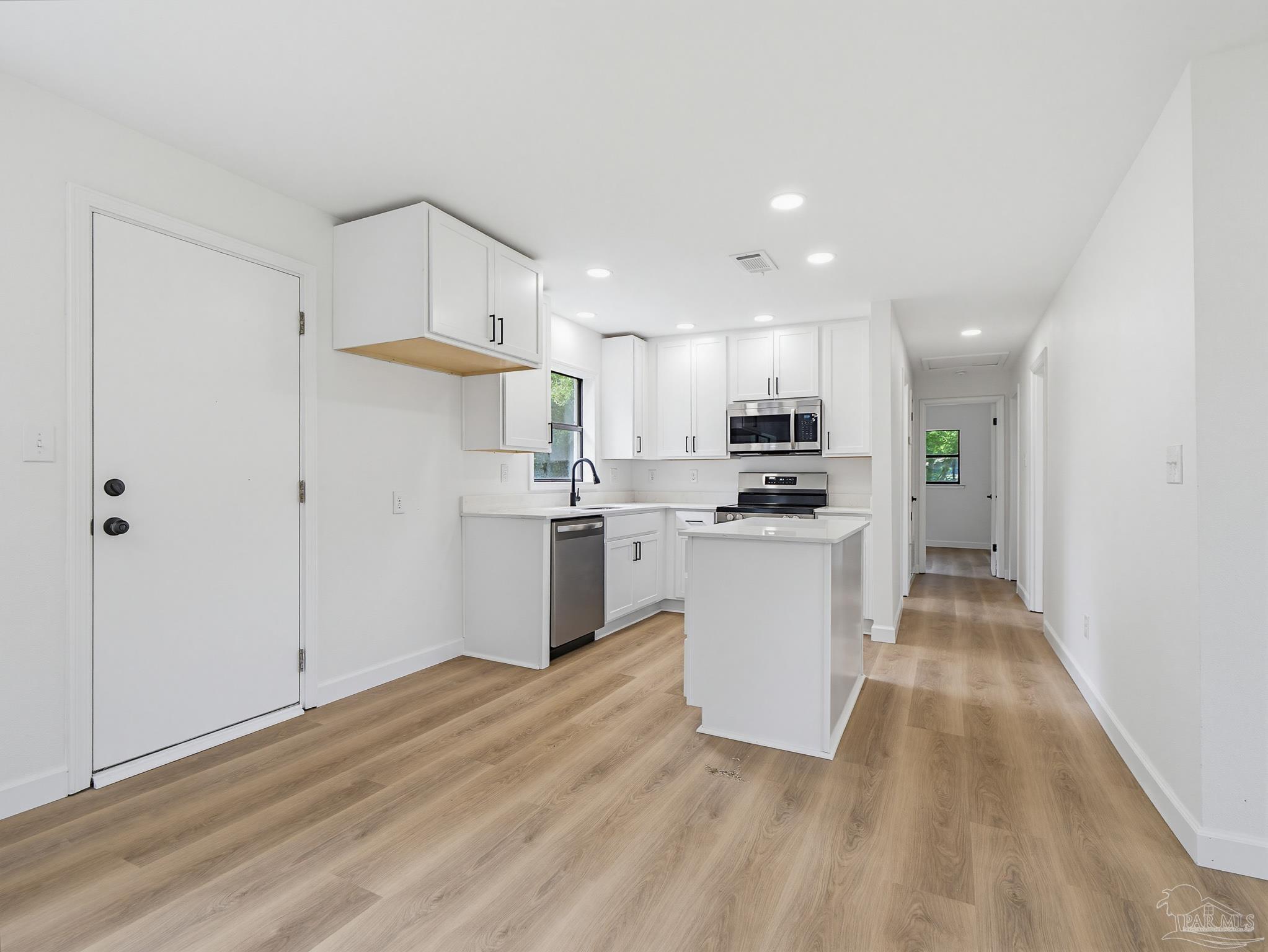 125 Madrid Road Cantonment, FL 32533 - Photo 8 of 16 a kitchen with white cabinets and stainless steel appliances