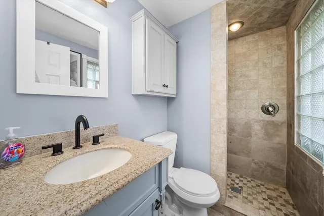 a bathroom with a granite countertop toilet sink and mirror