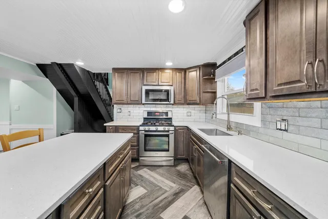 a kitchen with stainless steel appliances a sink dishwasher stove refrigerator and cabinets
