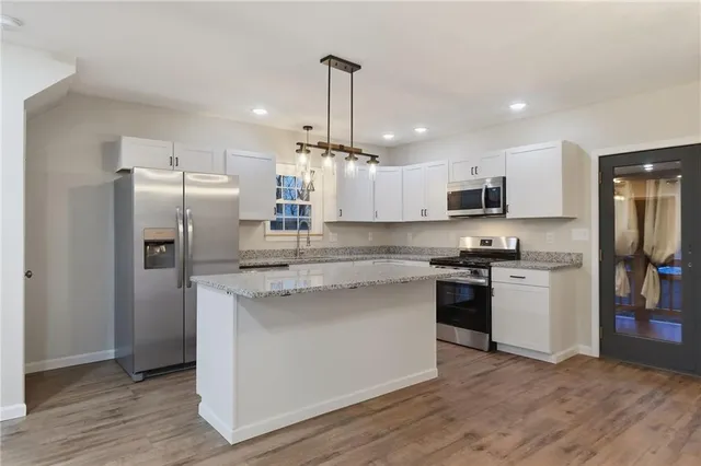 a kitchen with stainless steel appliances granite countertop a refrigerator a stove a sink and a microwave