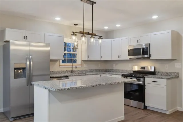 a kitchen with stainless steel appliances granite countertop a refrigerator a sink a stove a microwave and wooden floor