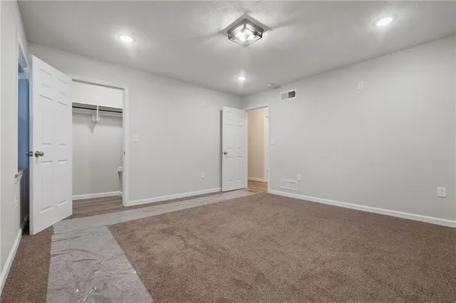 an empty room with a chandelier fan and windows