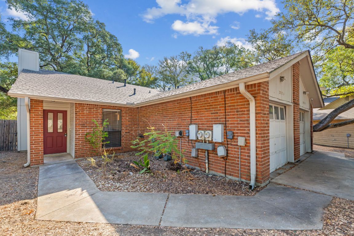 Single story home featuring a garage, a shingled roof, brick siding, and a chimney
